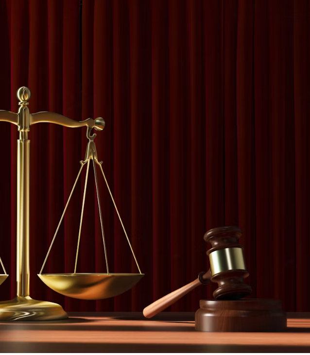 Golden scales of justice and a judge’s gavel against burgundy curtains